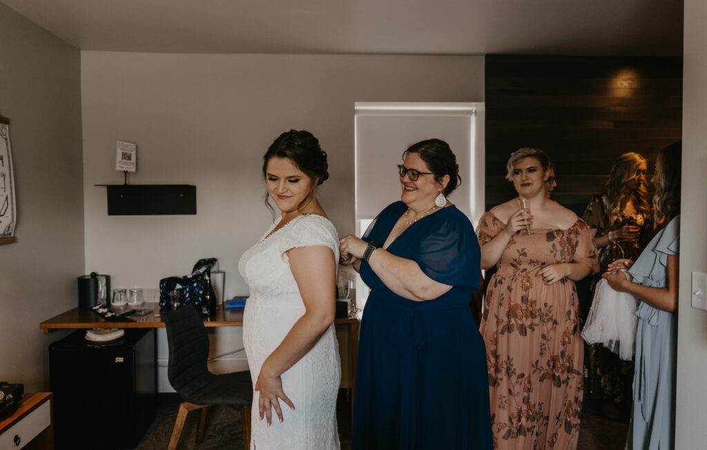 Bride getting into wedding dress and zipped up by mom.